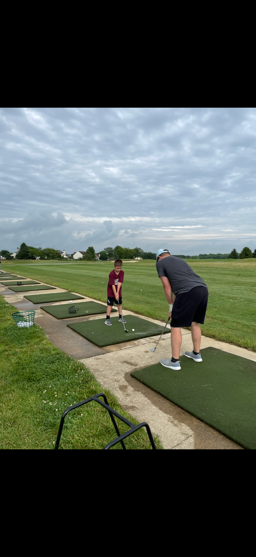 Coach working with a junior golfer at the driving range