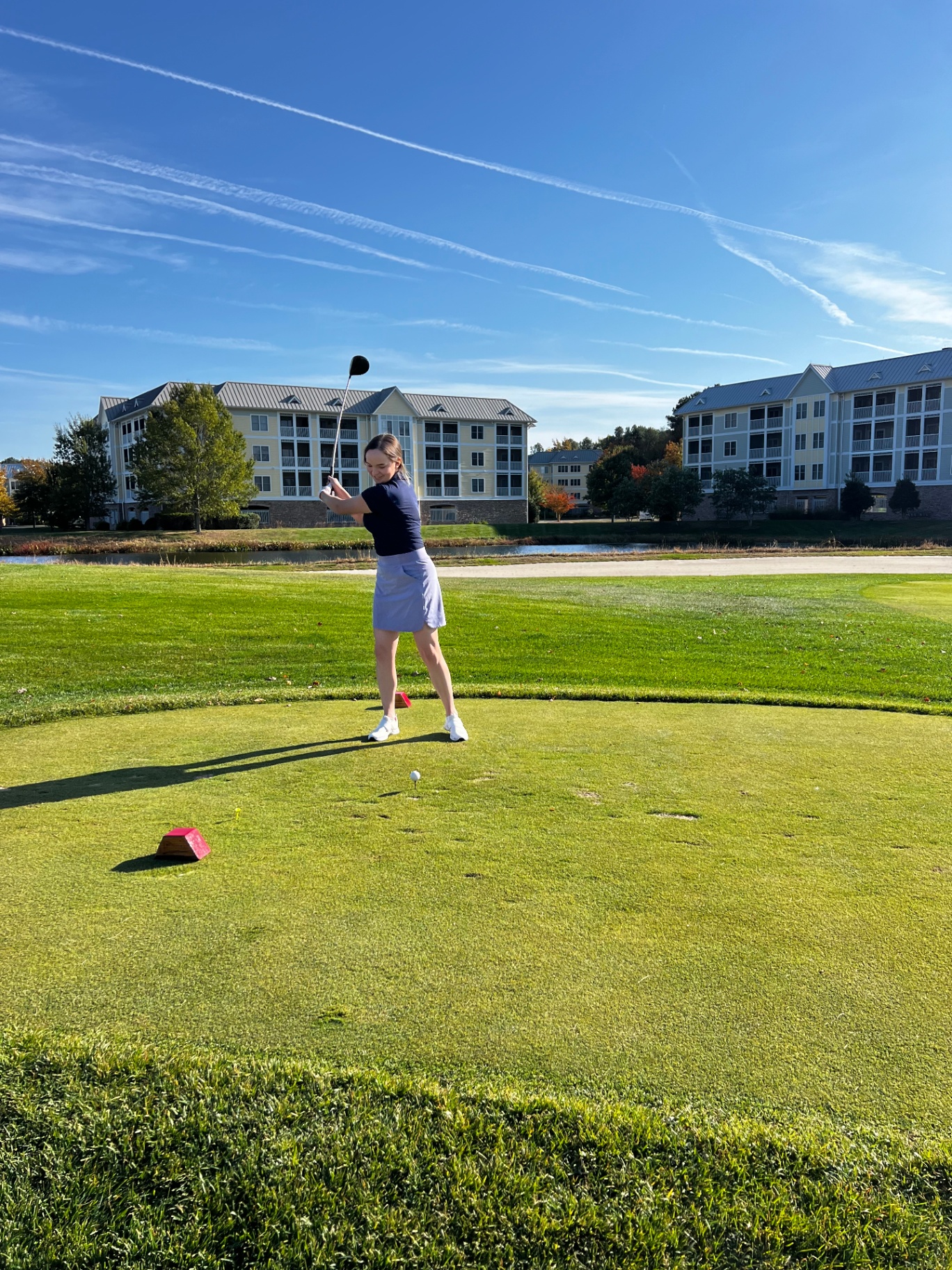 Golfer at the top of her backswing on the tee box
